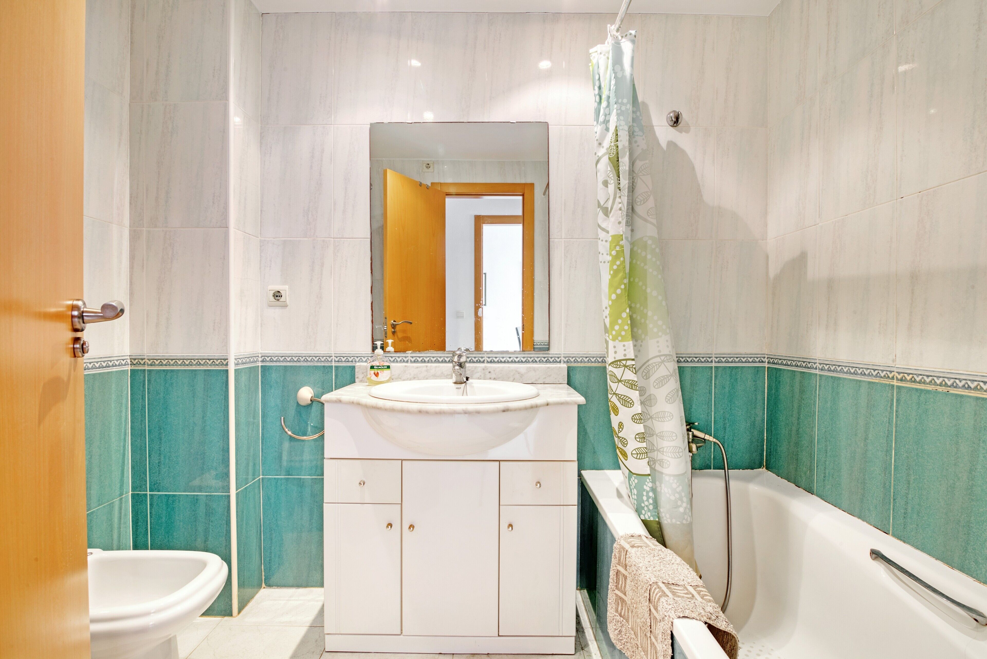 A bathroom with a sink, mirror, bathtub, and toilet.