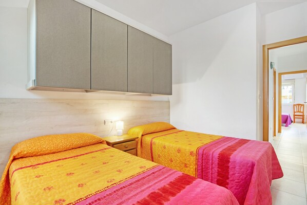 Une chambre avec deux lits, une armoire, une table de chevet et une chaise.