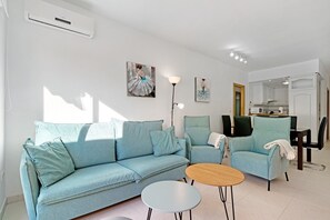 Ett vardagsrum med en soffa, fåtöljer, ett soffbord och konstverk på väggen.