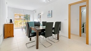 A dining area with a table, chairs, and a wooden cabinet. - Apartment "Brisas C2" with Shared Pool & Wi-Fi (Denia)