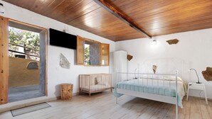 A bedroom with a wooden ceiling, a white bed, a wooden crib, a white nightstand, and a stone wall. - Holiday Studio 'Maya' with Sea View, Private Terrace and Wi-Fi (Guia)