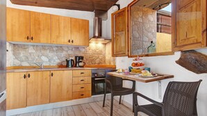 A kitchen with wooden cabinets, a stone backsplash, and a dining area with a table and chairs. - Holiday Studio 'Maya' with Sea View, Private Terrace and Wi-Fi (Guia)