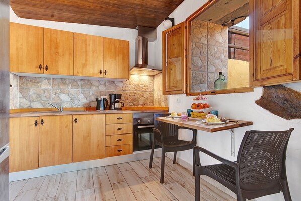 A kitchen with wooden cabinets, a stone backsplash, and a dining area with a table and chairs.