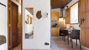 A kitchen with wooden cabinets, a stone backsplash, and a dining area with chairs. - Holiday Studio 'Maya' with Sea View, Private Terrace and Wi-Fi (Guia)