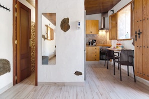 A kitchen with wooden cabinets, a stone backsplash, and a dining area with chairs.