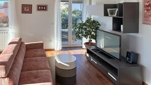 A modern living room with a pink sofa, a flat-screen TV, a coffee table, and a potted plant.