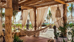 A wooden deck with a hammock, hanging lanterns, and potted plants. - Jungala Hotel at VidantaWorld Riviera Maya (Playa del Carmen)