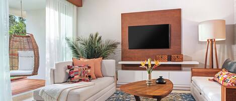 A modern living room with a sofa, a coffee table, a TV mounted on the wall, and a potted plant.