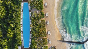 An aerial view of a resort with a long swimming pool, beach, and ocean. - Jungala Hotel at VidantaWorld Riviera Maya (Playa del Carmen)
