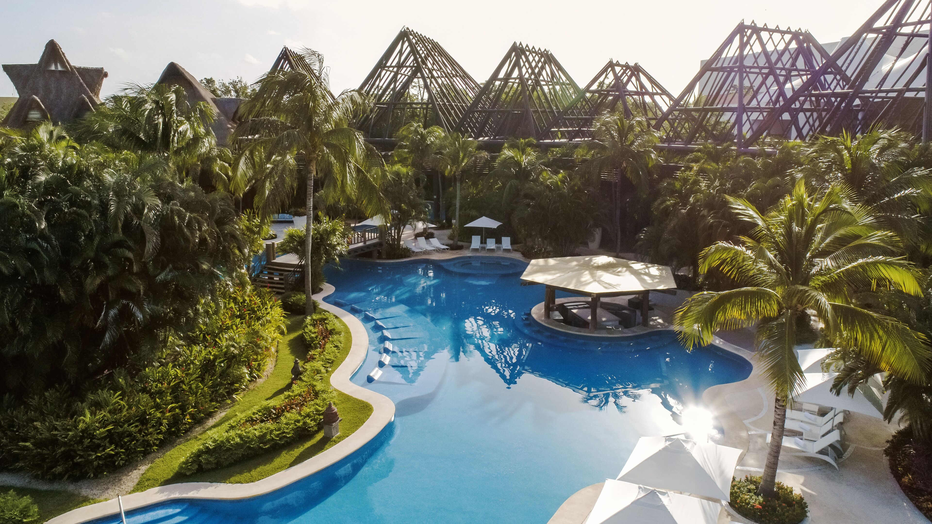 Piscina de un resort rodeada de palmeras y arquitectura moderna.