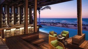 A bar area with a pool and beach view. - Jungala Hotel at VidantaWorld Riviera Maya (Playa del Carmen)
