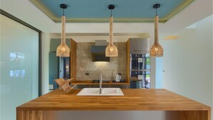 A modern kitchen with a central island, three hanging pendant lights, and a view of the adjacent living area. - Nice home in Svetvincenat with sauna (Svetvincenat)