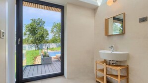 A bathroom with a large window, a white sink, and a wooden shelf. - Nice home in Svetvincenat with sauna (Svetvincenat)