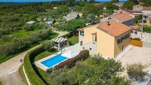 A residential area with a house featuring a swimming pool, surrounded by greenery and a clear view of the sea. - Nice home in Porec with sauna (Porec)