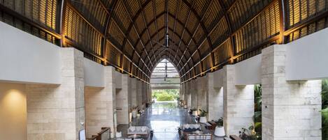 A spacious lobby with high ceilings, stone columns, and a central seating area with sofas and tables.