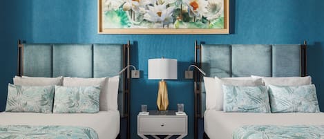 A hotel room with two beds, a nightstand with a lamp, and a framed floral artwork on the wall.