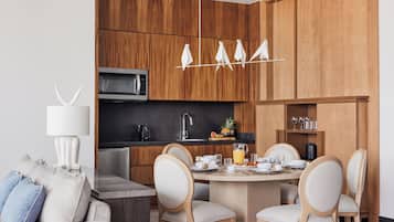 Una cocina moderna con armarios de madera, una zona de comedor con una mesa redonda y sillas, y un microondas empotrado.