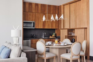 Una cocina moderna con armarios de madera, una zona de comedor con una mesa redonda y sillas, y un microondas empotrado.