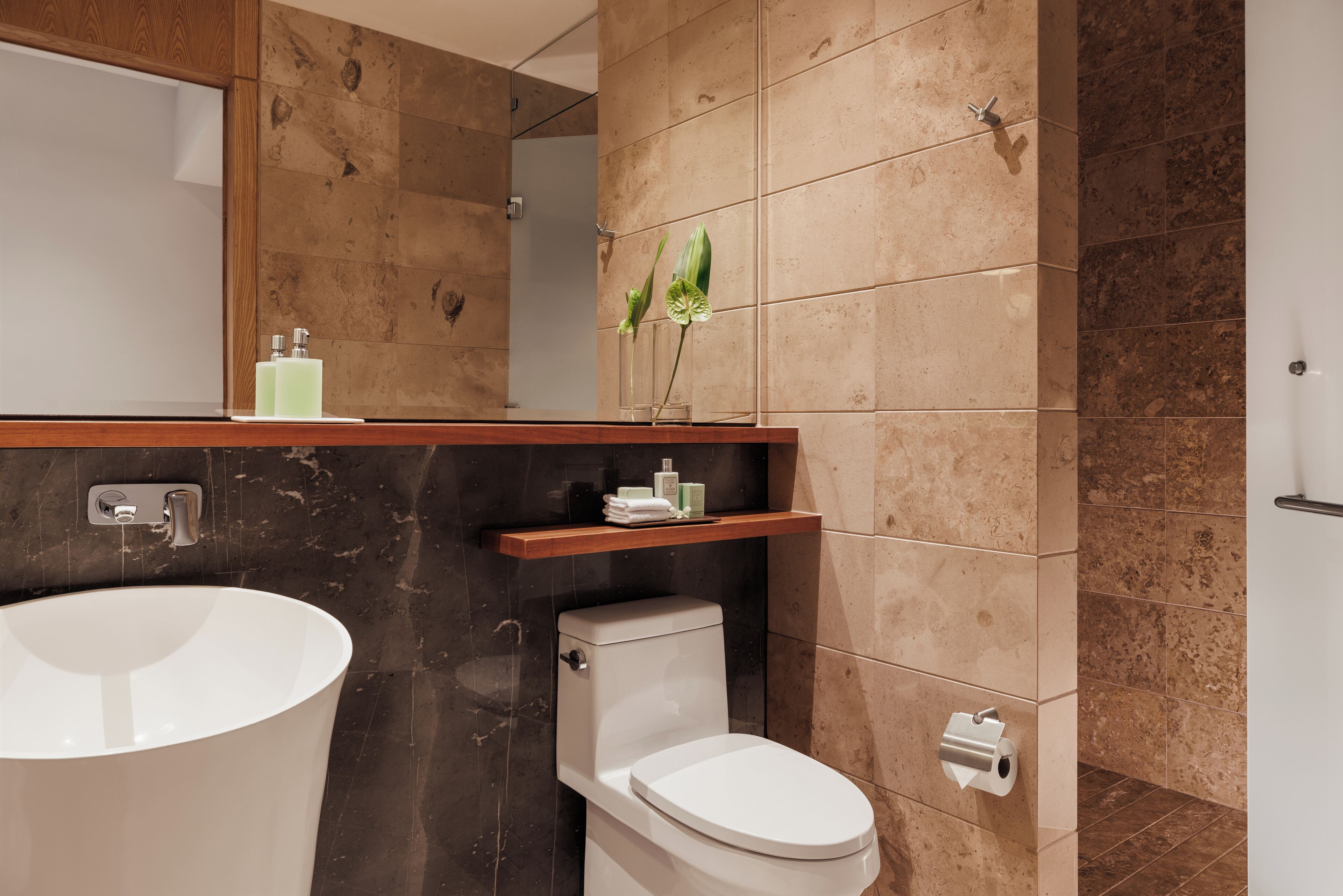 A modern bathroom with a freestanding bathtub, a toilet, and a vanity with a mirror and shelves.