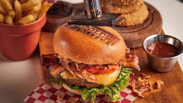 A burger with bacon, cheese, lettuce, and fried onions, served on a checkered paper.