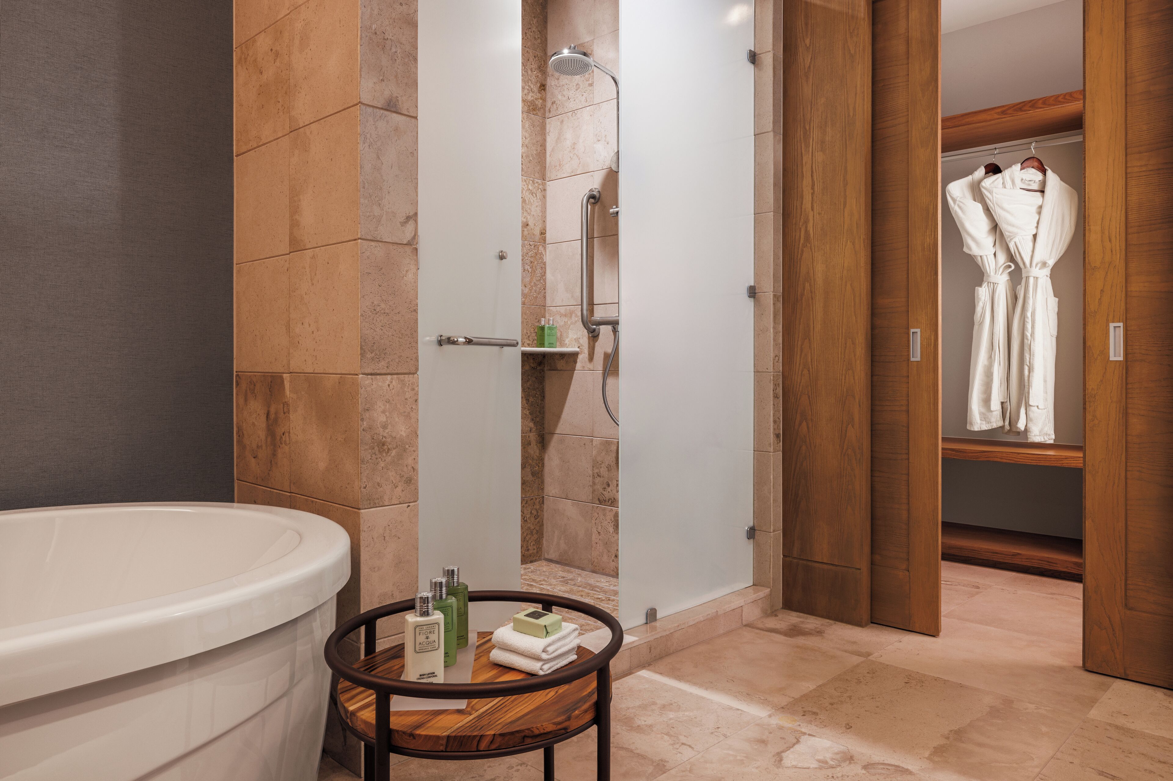 A modern bathroom with a freestanding bathtub, a shower enclosure, and a wooden vanity with toiletries.