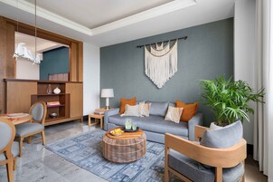Una sala moderna con un sofá gris, un aparador de madera y una mesa de centro redonda.
