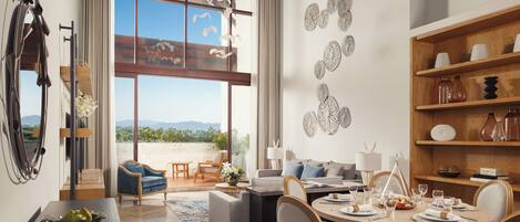 A modern living room with a dining area, large windows, and a view of the outdoors.
