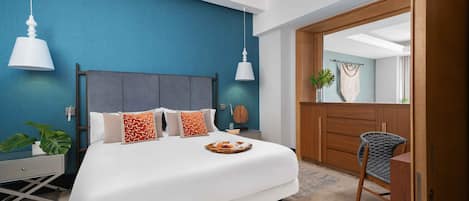 A modern bedroom with a large bed, two pendant lights, a wooden wardrobe, and a mirror.
