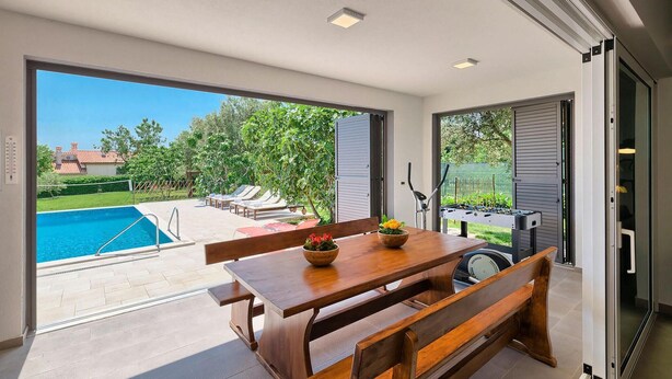 Un espace repas avec vue sur la piscine, une table avec des chaises et un banc.