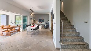 Une cuisine moderne avec un coin repas, un escalier et un téléviseur en arrière-plan.