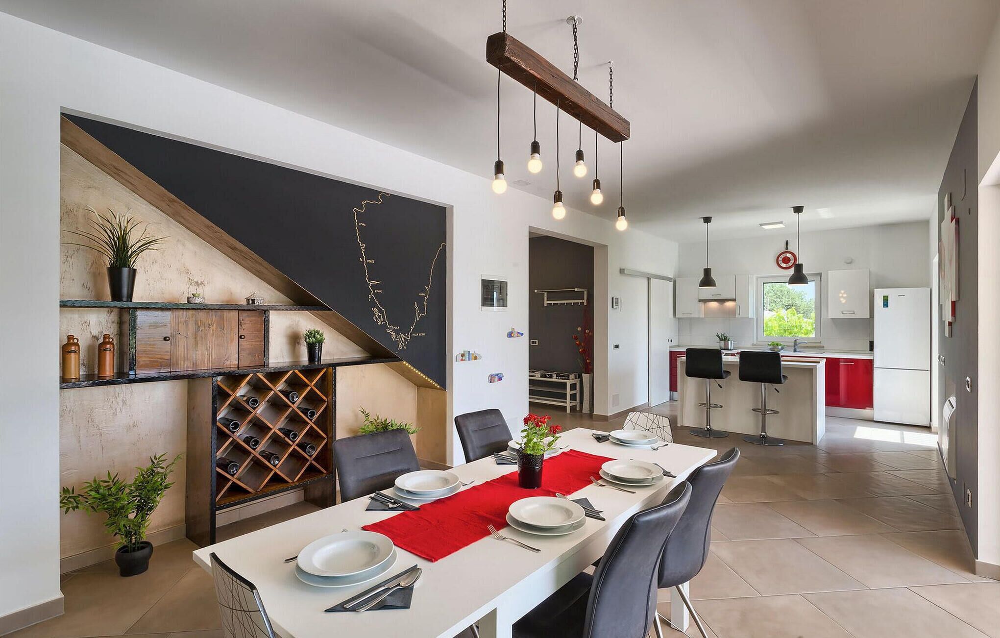 A modern kitchen with white cabinets, a red island, and a dining area with a white table set for four.