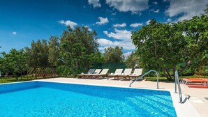 Une piscine d’un bleu éclatant, dotée de chaises longues et d’une terrasse en bois.