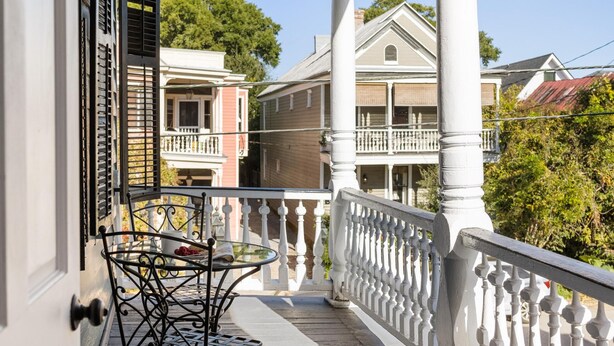 A covered porch with a white balustrade, a hanging lantern, and a table with chairs. - Pet-Friendly +Historic Charm & Modern Comfort Near Upper King (Charleston)