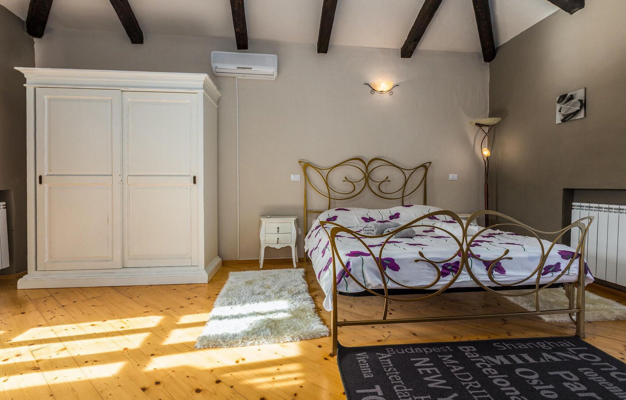 A bedroom with a bed, wardrobe, bedside table, and a radiator.