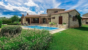 Une villa en pierre dotée d’une piscine, d’un espace extérieur aménagé et d’un jardin bien entretenu.