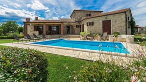 Une maison en pierre avec une piscine, un espace extérieur aménagé et un jardin bien entretenu.