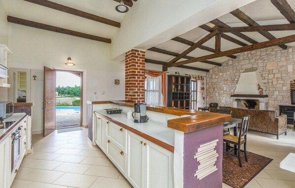 A spacious kitchen with a central island, a stone fireplace, and a view of a pool. - Pet friendly home in Vizinada (Vizinada)