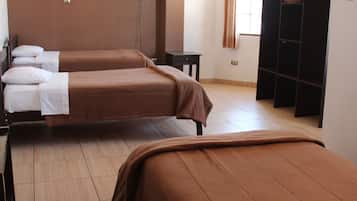 A hotel room with two beds, a TV mounted on the wall, and a wardrobe.