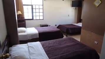 Habitación de hotel con dos camas, una ventana con cortinas, un televisor montado en la pared y una mesita.