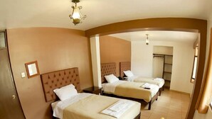 Habitación de hotel con dos camas, una araña y un jarrón de rosas.