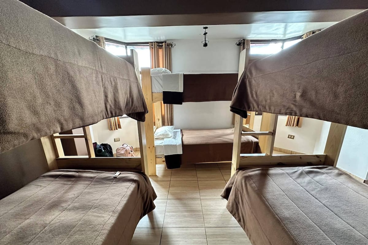 A dormitory-style room with bunk beds, wooden walls, and a tiled floor.