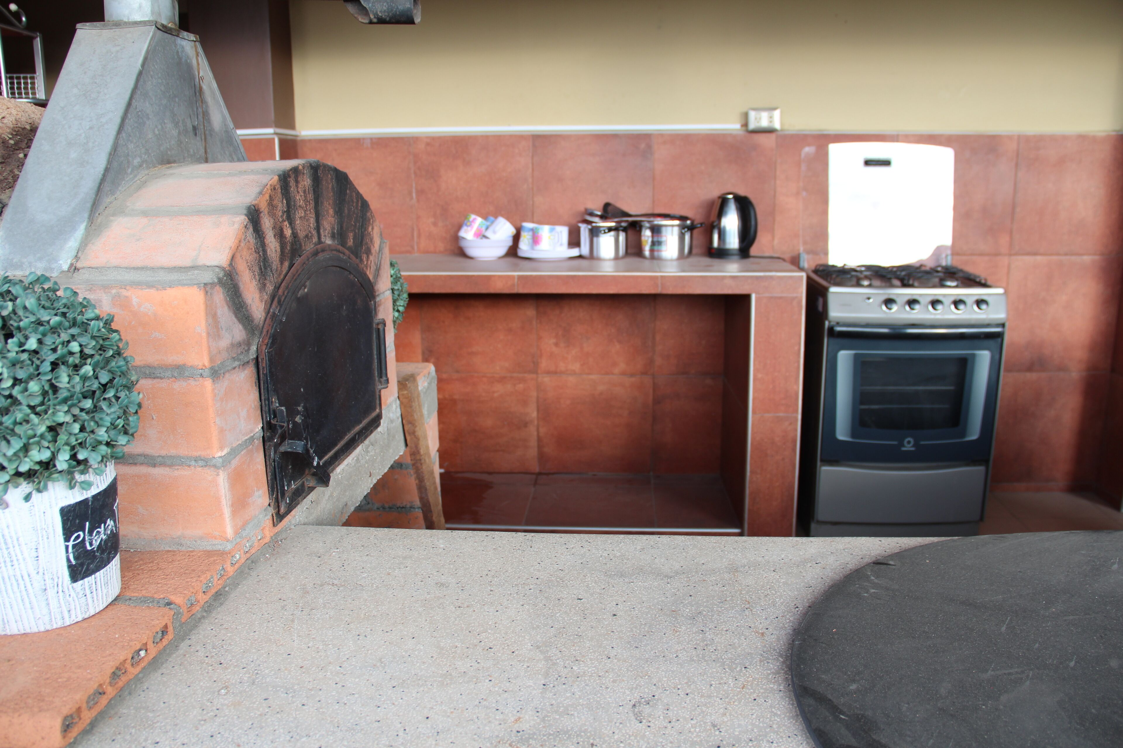 Una cocina con horno de ladrillo, estufa y diferentes utensilios de cocina.