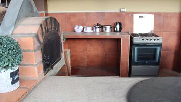 Una cocina con horno de ladrillo, estufa y diferentes utensilios de cocina.