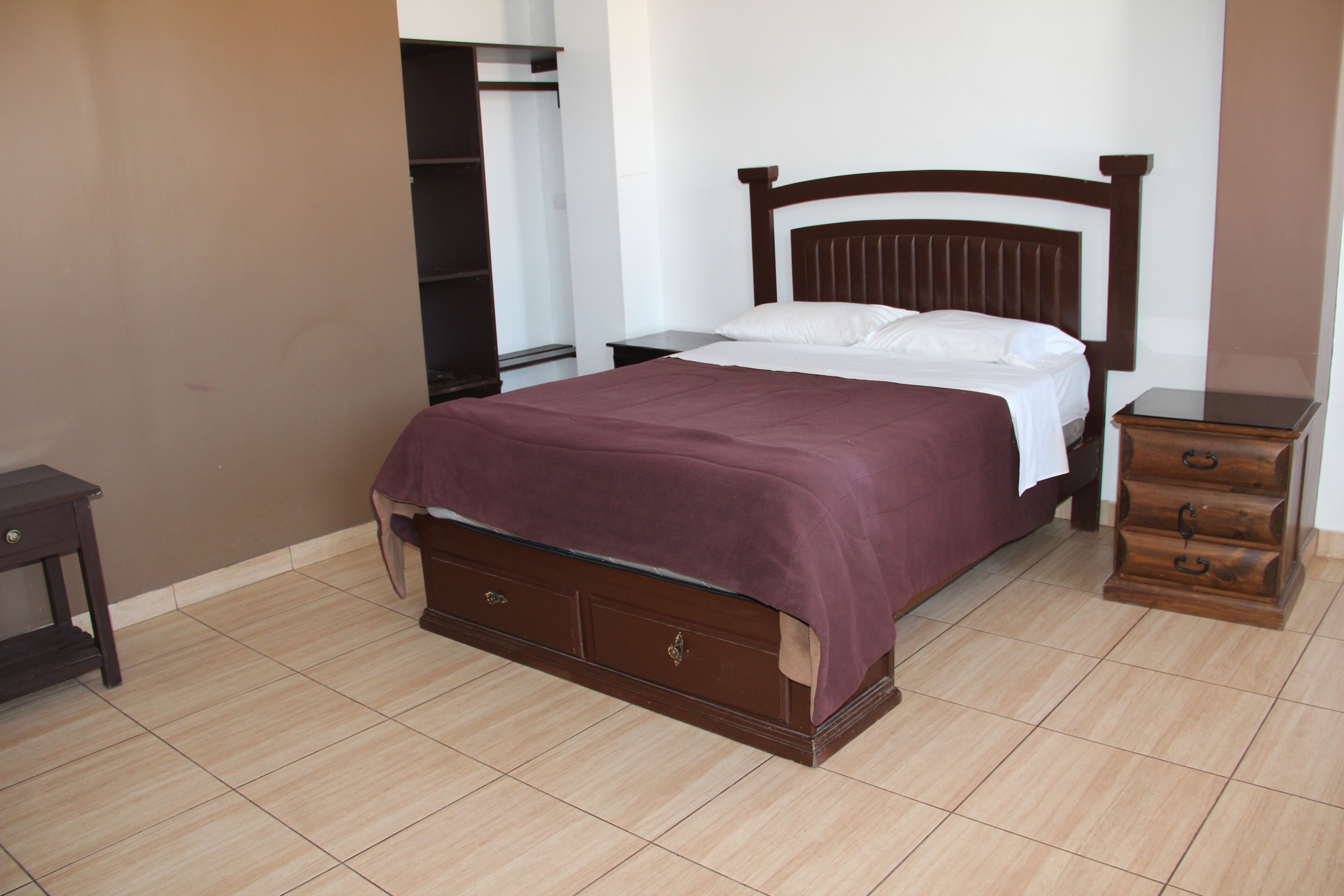 A bedroom with a wooden bed, a nightstand, a dresser, and a wardrobe.