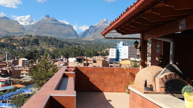 Terraza en la azotea con horno de ladrillo, con vistas a un paisaje montañoso y un pueblo.