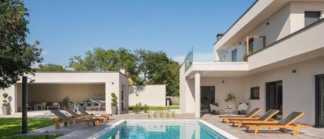 Ein moderner Poolbereich mit Liegestühlen und einem klaren, blauen Pool.