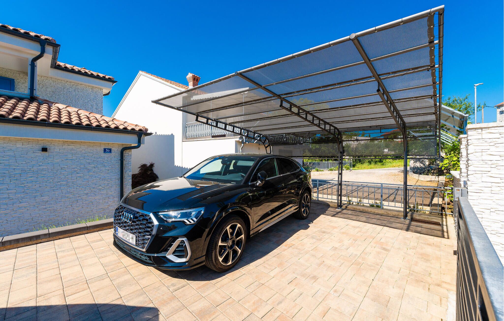 A black SUV parked under a covered parking area with a clear blue sky.