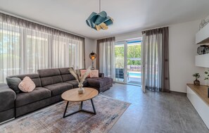 A modern living room with a sofa, coffee table, and a view of a swimming pool.