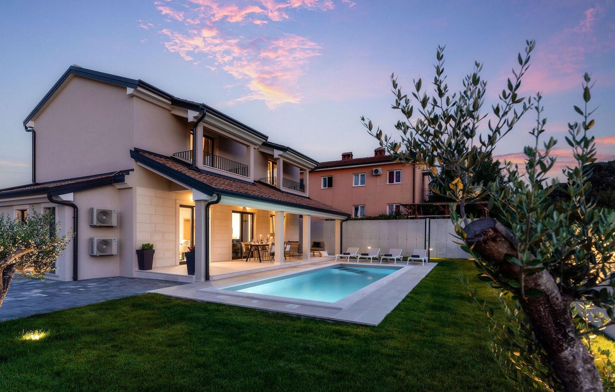 Una casa a due piani con piscina, patio coperto e prato curato.