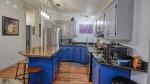 Una cocina moderna con armarios azules, encimera de granito y electrodomésticos de acero inoxidable.